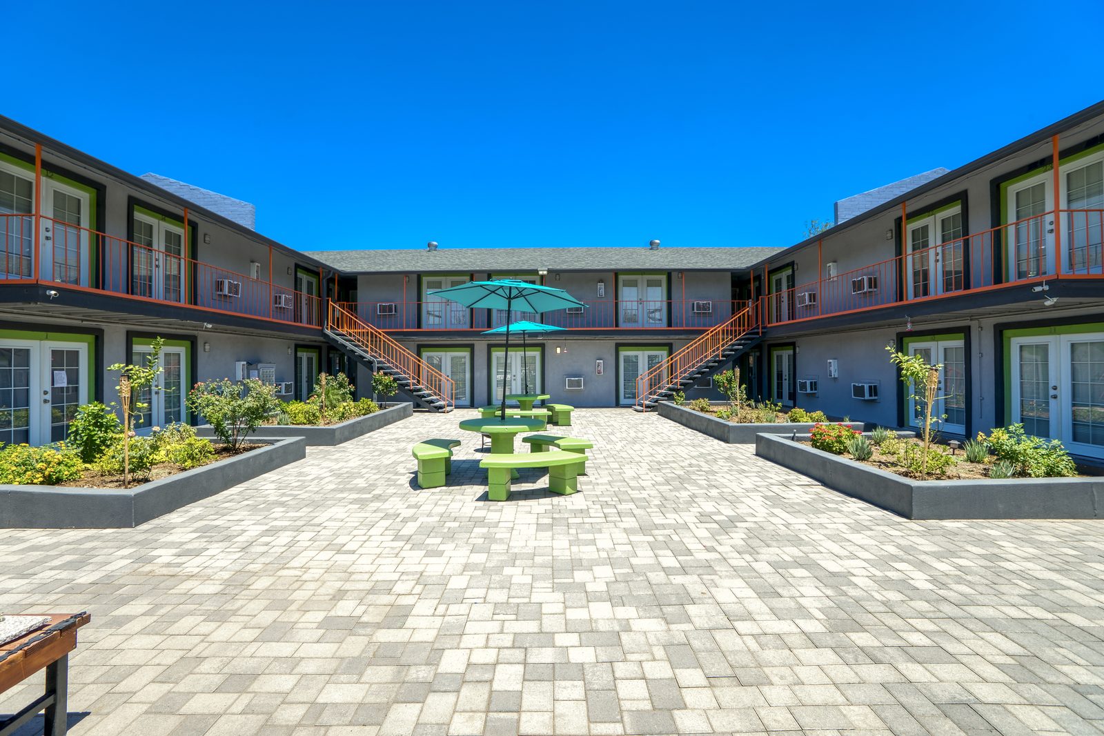 Spacious paved courtyard with green picnic tables at Lucky Star Flats apartments in Phoenix