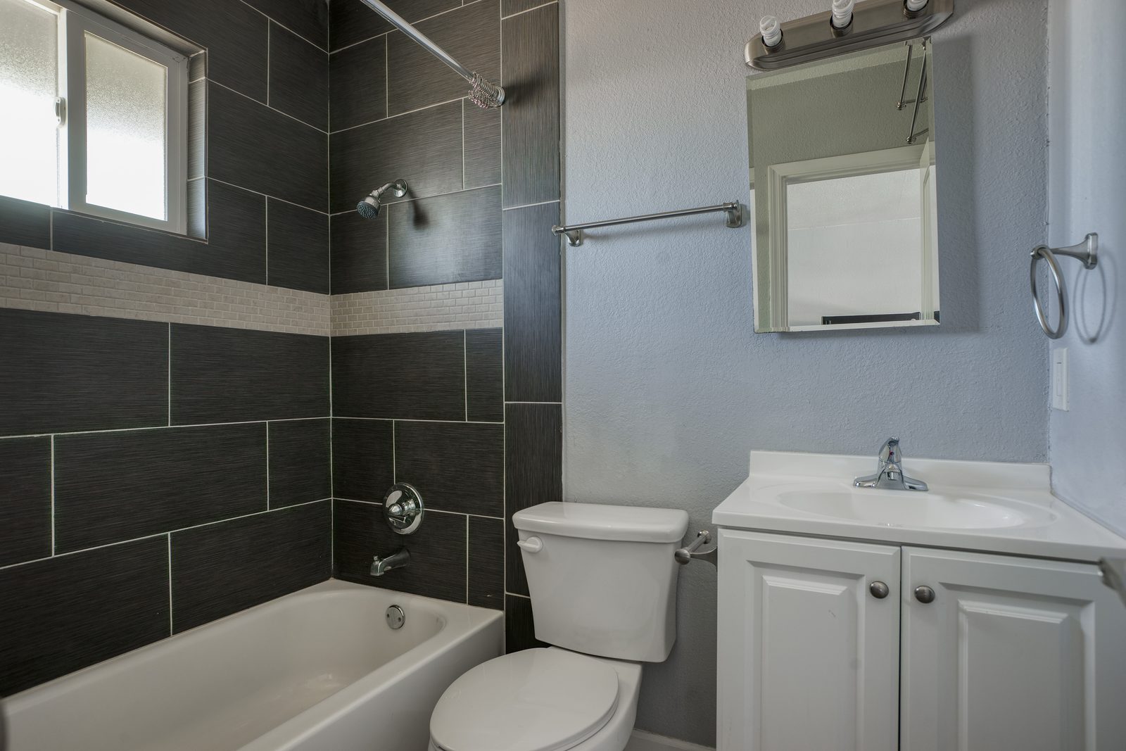 Remodeled bathroom with dark tile shower, vanity, and medicine cabinet in Phoenix studio apartment